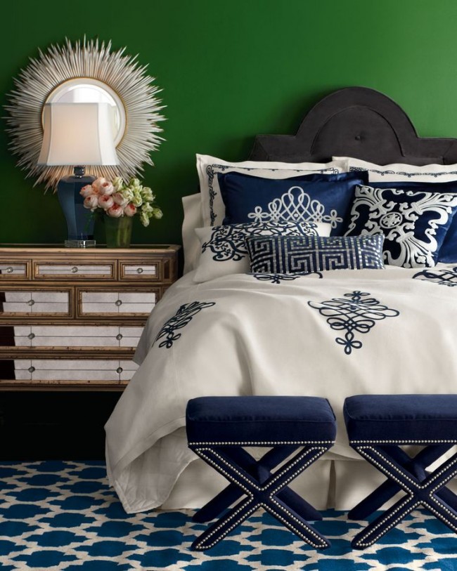 Šedá postel s bílým a modrým ložním prádlem v zelené ložnici