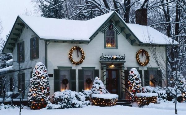 Załóż oświetlenie zewnętrzne na Boże Narodzenie - 30 świątecznych pomysłów i wskazówek biały dom pokryty śniegiem z małymi żółtymi światełkami
