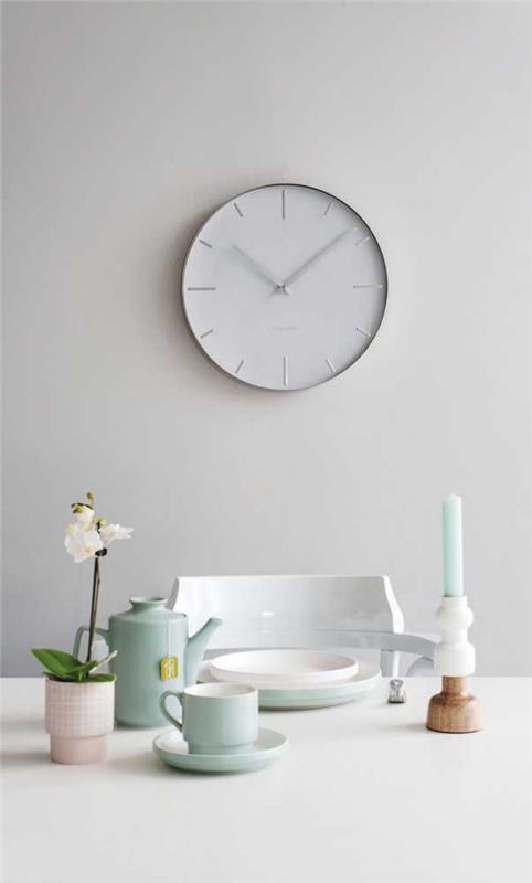 Biały zegar ścienny z naczyniami na stole