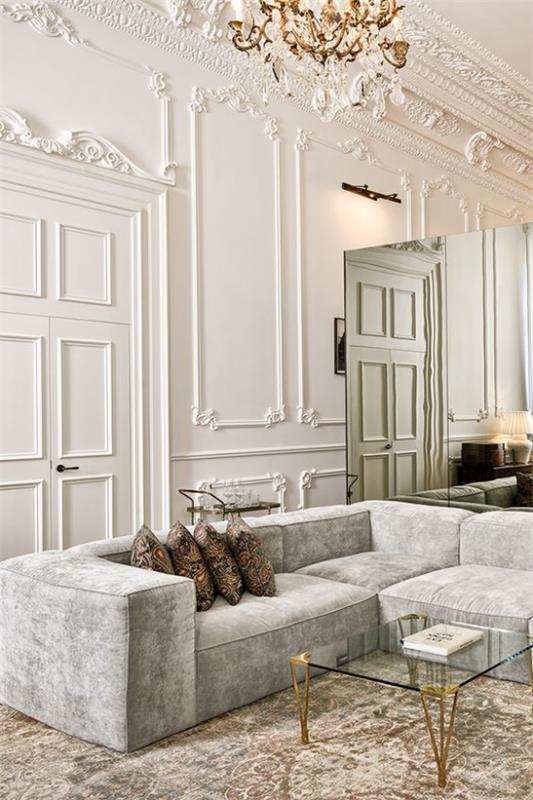 Francuski szyk we wnętrzu, pozłacane akcenty kryształowego żyrandola i eleganckiego stolika kawowego
