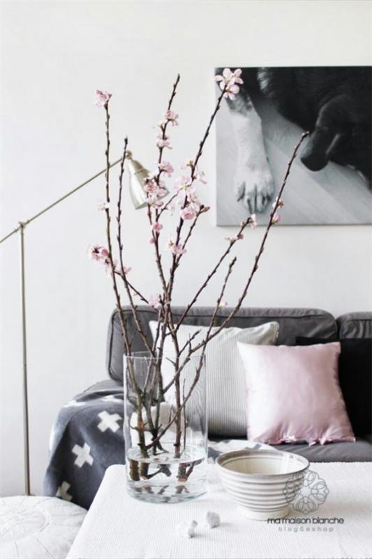 Wiosenna dekoracja z kwiatami wiśni kilka gałązek wiśni w szkle w salonie na stoliku kawowym