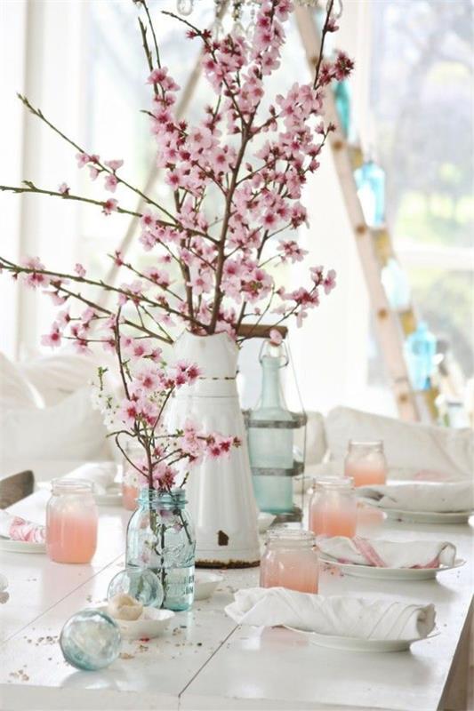 Wiosenne dekoracje z kwiatami wiśni w różnych naczyniach zdobią stół w rustykalnym stylu
