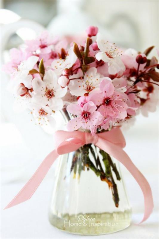 Wiosenna dekoracja z różowymi kwiatami wiśni w szklanej różowej wstążce