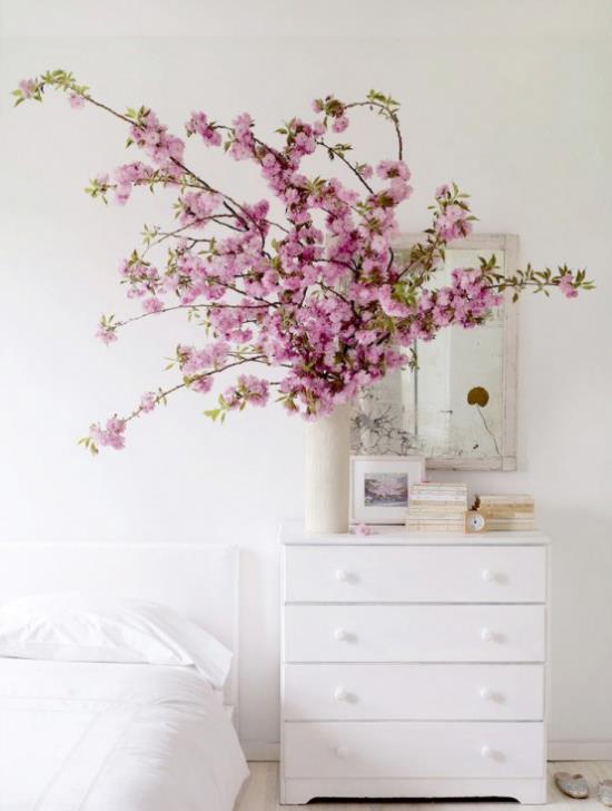 Wiosenna dekoracja z różowymi kwiatami wiśni w wazonie białe lustro ścienne kredens