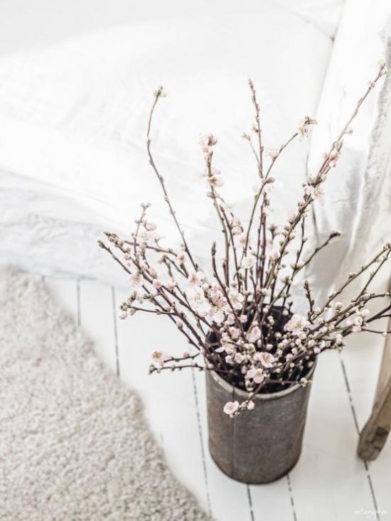 Wiosenna dekoracja z białymi kwiatami wiśni w starym naczyniu w salonie
