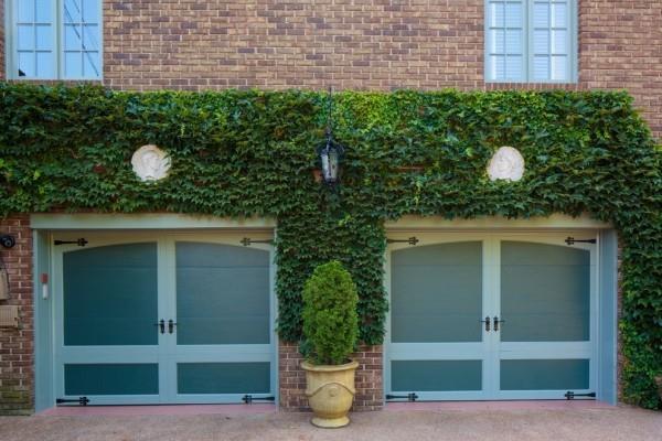 L'écologisation des murs attrayants du garage entre les portes du garage est un pot de fleurs avec du thuya à feuilles persistantes