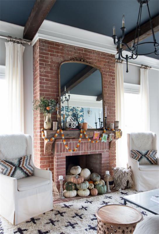Décoration d'automne dans le salon citrouilles de différentes couleurs et tailles dans la cheminée