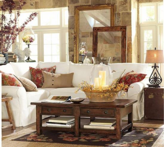 Décoration d'automne dans le salon canapé d'angle blanc table en bois décorée d'oreillers colorés bougies branches dans un vase confortable et confortable