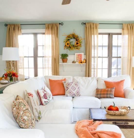 Herbstdeko dans le salon canapé d'angle blanc coussins colorés jeter couverture en couronne d'automne orange sur le mur