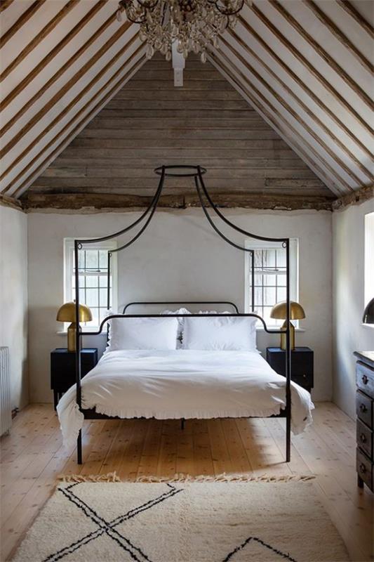 Metalowe łóżko z baldachimem biała pościel rustykalna sypialnia spadzisty sufit