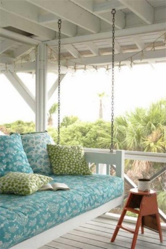 Lit suspendu à l'extérieur sur la terrasse couverte tapisserie d'ameublement hauteur parfaite coussins décoratifs table d'appoint
