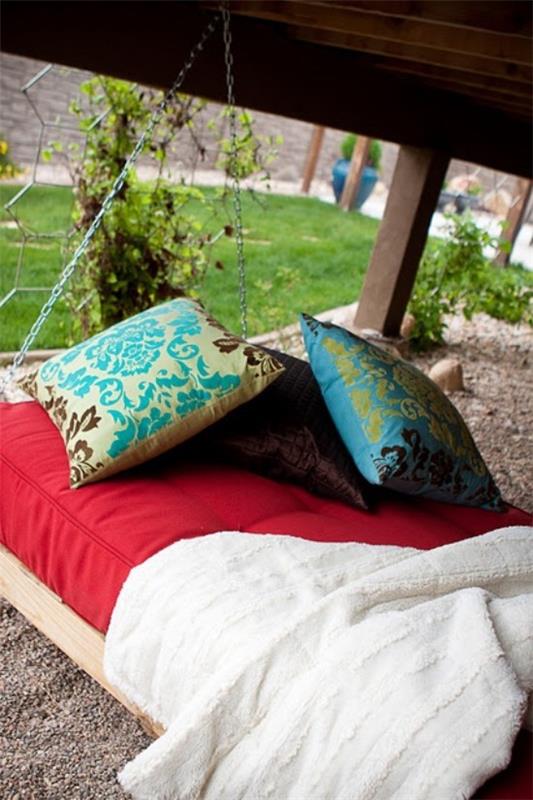 Lit suspendu à l'extérieur avec des oreillers colorés comme décoration jardin verdoyant en arrière-plan