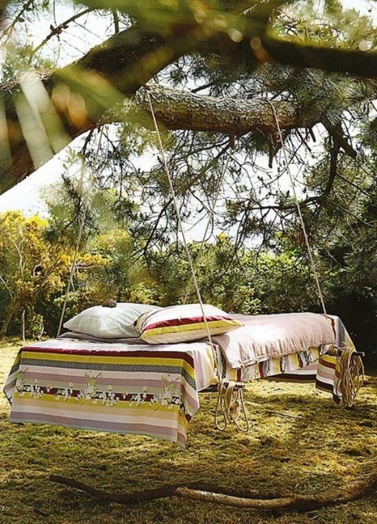 Wiszące łóżko na zewnątrz w ogrodzie na drzewie w stylu boho wygląda zachęcająco