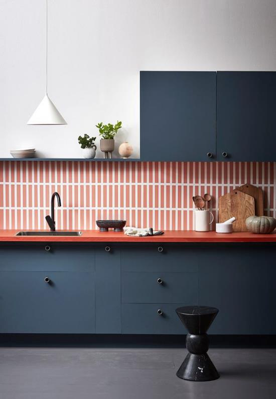 Aneks kuchenny nowoczesny design z mocnym kontrastem kolorystycznym ciemnoniebieskie pomarańczowe płytki ścienne w paski drewniane deski