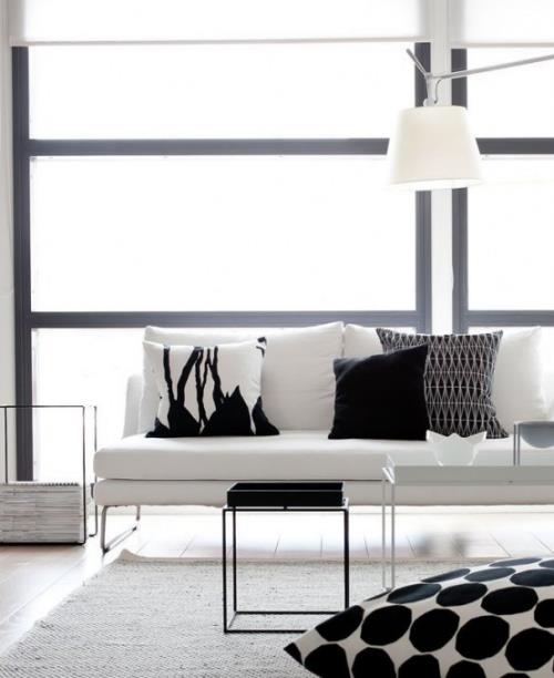 Minimalizm w kolorystyce salonu w bieli i jasnoszarych poduszkach dekoracyjnych w czerni i bieli z prostym wzorem