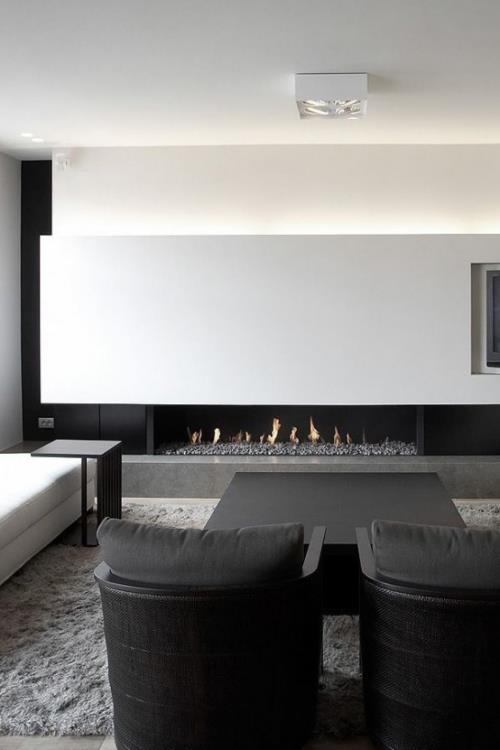 Minimalizm w salonie idealny projekt pokoju biały szary dwa czarne fotele na pierwszym planie kominek w tle