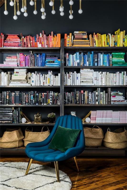 Les livres de bibliothèque de fauteuil bleu de bibliothèque à la maison moderne organisent par couleurs