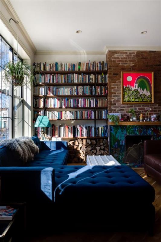 Bibliothèque à la maison moderne un mur avec des livres à côté de la cheminée canapé confortable en lumière bleu marine