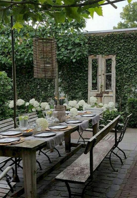 Tendances extérieures 2020 célébrer à l'extérieur organiser des repas ensemble table joliment dressée mur de lierre comme écran d'intimité