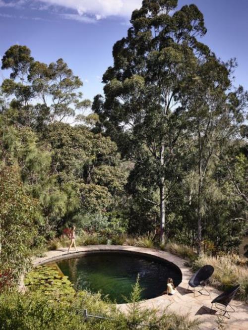 Okrągłe baseny ogrodowe, okrągły basen wpuszczony w ziemię, obok niego dwa krzesła, dużo zieleni, wysokich drzew
