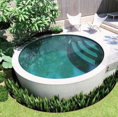 Okrągłe baseny ogrodowe kompaktowy kształt schody dwa leżaki obok dużo zieleni dookoła