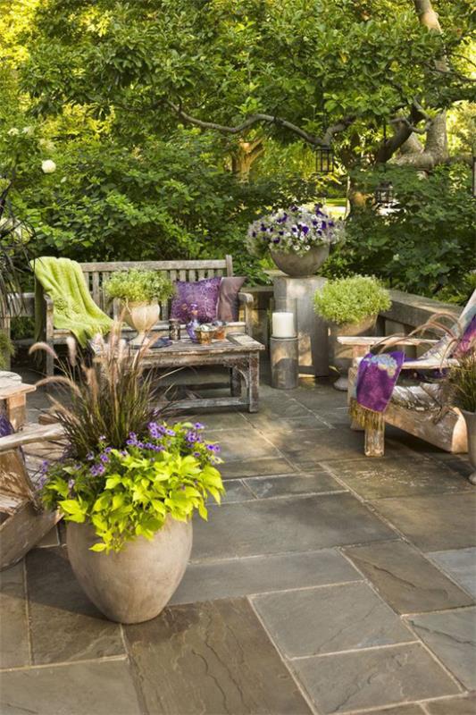 Stare drewniane pojemniki meblowe z kwiatami i zielonymi roślinami sprawiają, że patio nadaje się na wiosnę