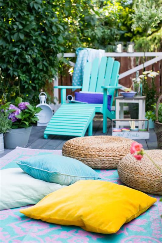 Taras jest gotowy na wiosnę z jasnoniebieskimi leżakami wykonanymi z drewna, wieloma kolorowymi poduszkami do siedzenia, jasnoniebieskim żółtym plecionym, tworzącym przyjemną atmosferę