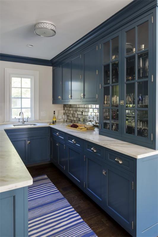 Podziemna kuchnia ciemnoniebieskie szafki kuchenne w paski biegacz małe okno białe blaty