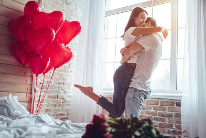 Amoureux de son signe du zodiaque pour la saint valentin ballons rouges roses rouges heureux son jeune couple dans la chambre