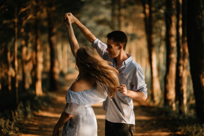 Amoureux, son jeune couple heureux danse dans la forêt avec des lunettes roses