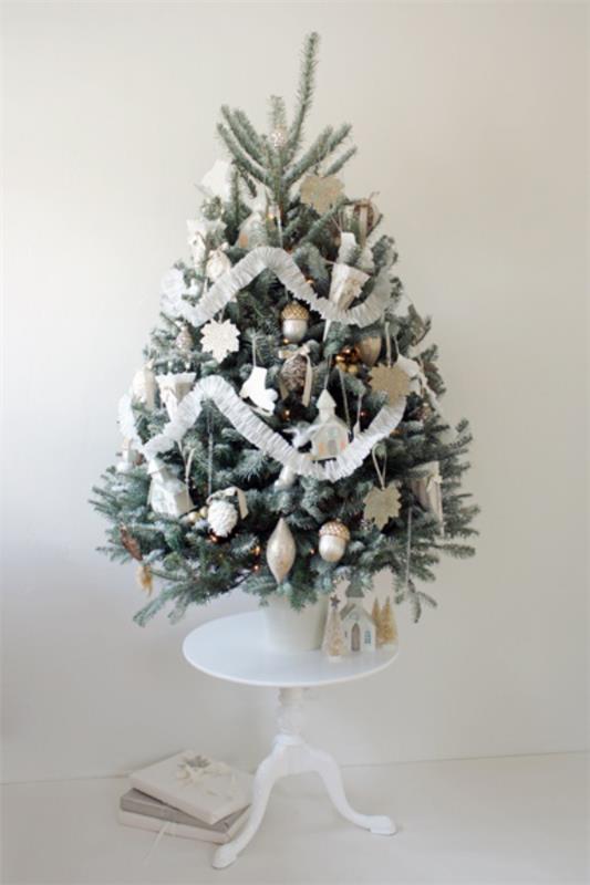 Sapin de Noël décorer joliment décoré en petit sapin de Noël blanc et argent placé sur une petite table ronde