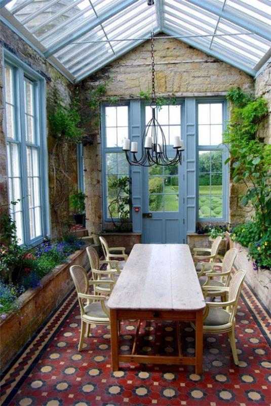 Jardin d'hiver pour câliner ambiance rustique coin repas très invitant table chaises de nombreuses plantes vertes des deux côtés mur de pierre mosaïque de sol