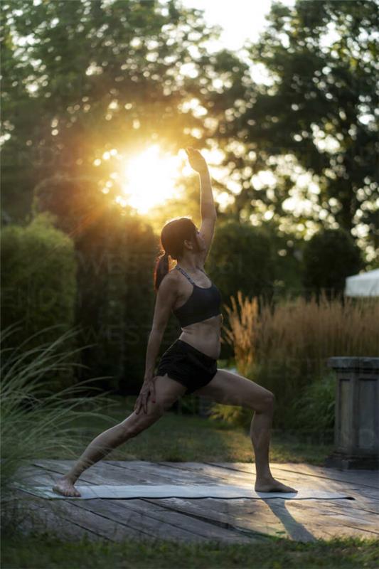 Jardin de yoga exposer et concevoir au coucher du soleil des exercices de tapis de yoga pour jeunes femmes à l'extérieur