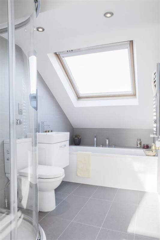 Design d'intérieur contemporain, salle de bain lumineuse toute en blanc Baignoire sous le toit en pente Coin douche derrière paroi vitrée