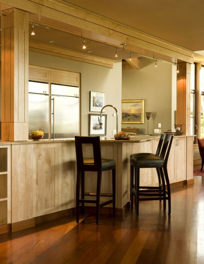 Eine Bartheke kombiniert mit einem Küchenset in einer modernen Küche. Stromschienen-Beleuchtungssystem mit schwenkbaren Leuchten über der Oberfläche montiert