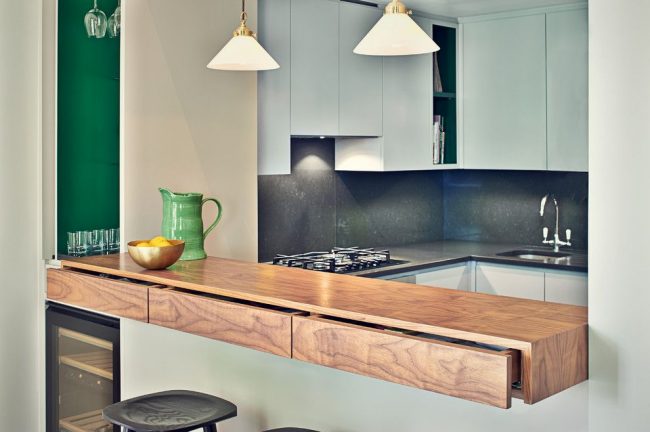 Moderne Küche mit Kunststofffront und mittelgroßer Holzarbeitsplatte. Glaskonsole mit ausziehbaren Ablagen. Merkmal der Bartheke in Schubladen, die in die Arbeitsplatte integriert sind