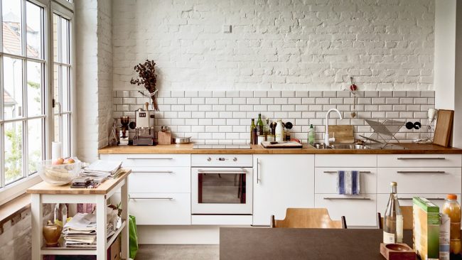Bílá kuchyně ve stylu podkroví v kombinaci s dřevěnou pracovní deskou