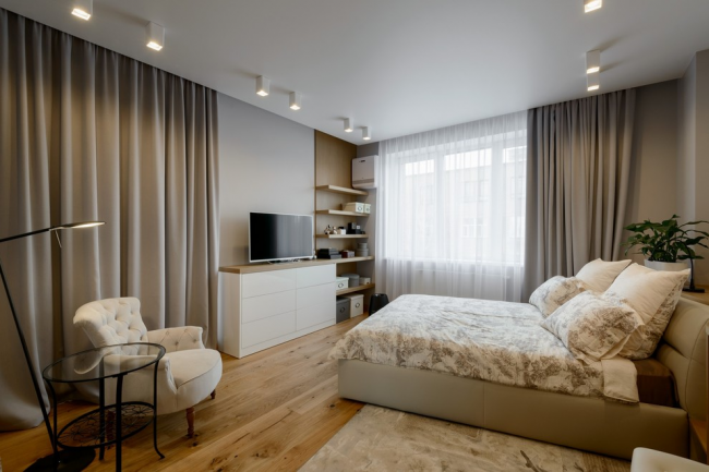 Prostorná moderní ložnice s bílou komodou naproti posteli