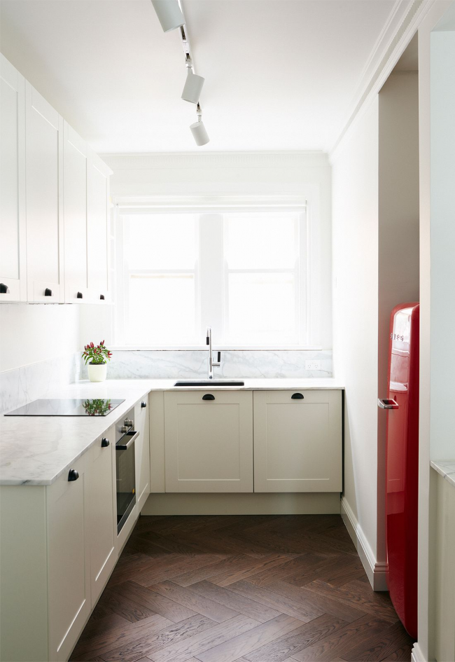Смело решение за малка светла кухня - фокусиране на цялото внимание върху червения хладилник