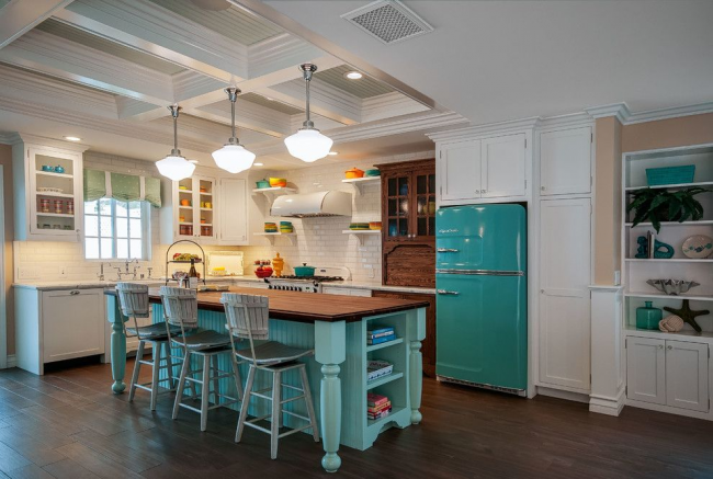 Просторна студийна кухня в светли цветове с ярки акценти върху тюркоазения хладилник и трапезария в същия цвят