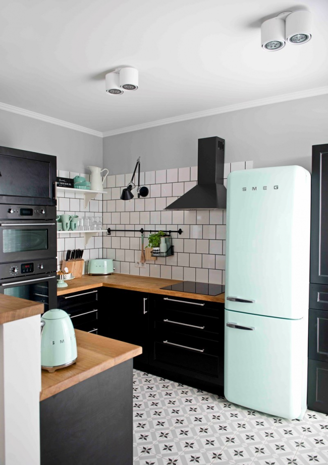 Голям марков хладилник на марката Smeg в кухнята в черно -бели мотиви с елементи на слушалки от естествено дърво