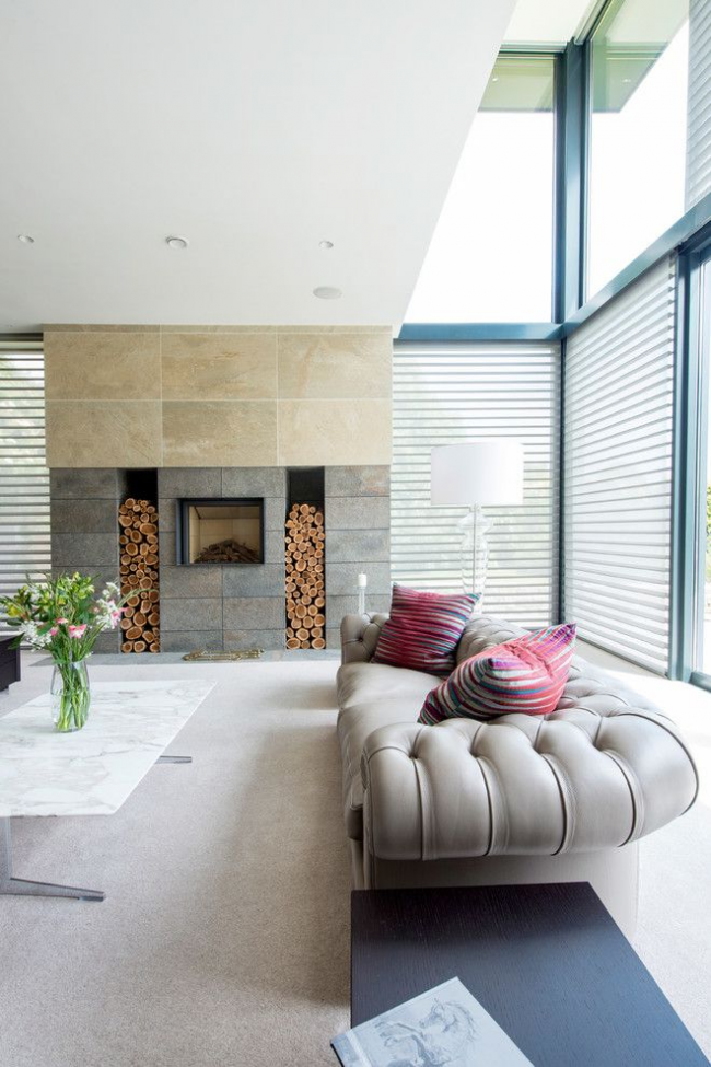 Prostorný interiér obývacího pokoje soukromého domu se šedou pohovkou Chesterfield v moderním designu
