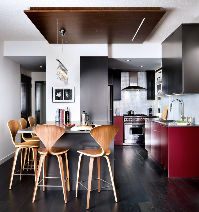 Útulná studiová kuchyně v malém bytě. Odvážné a jasně červené akcenty na prvcích kuchyňské soupravy vypadají v celkovém interiéru velmi organicky