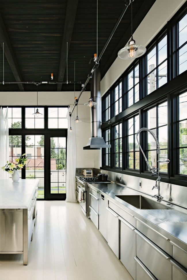 Velká moderní černobílá kuchyně v soukromém domě s velkými okny, která zajišťují maximální přirozené světlo během dne