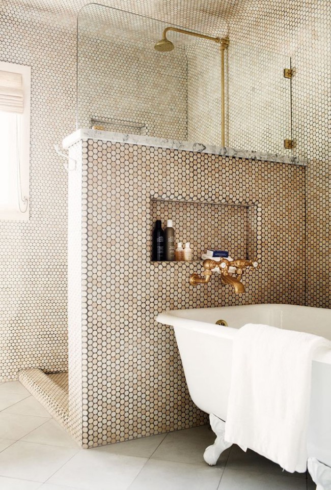 Místnost ve zlaté mozaice s nízkou přepážkou mezi koupelnou a sprchovým koutem