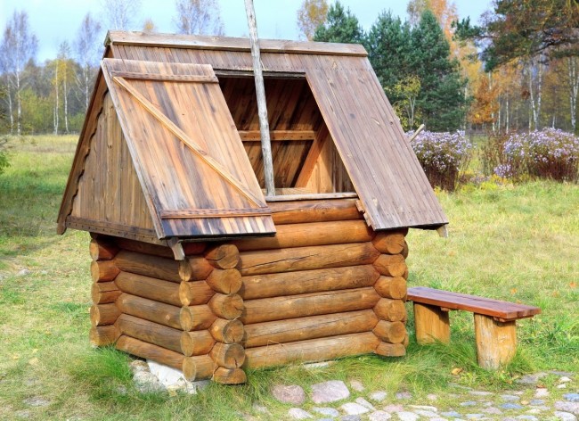 Haus für einen Brunnen in Form eines viereckigen Blockhauses und eines verzierten Daches