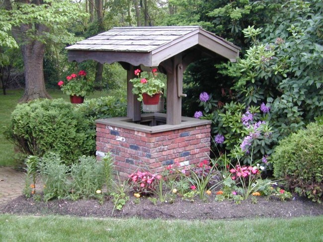 Schönes Haus für einen Brunnen, geschmückt mit Blumen