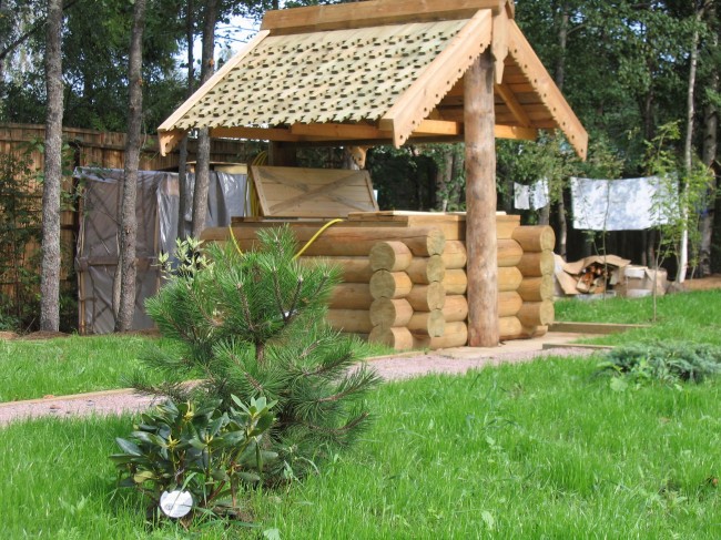 Schönes Holzhaus für einen Brunnen mit geschnitzten Elementen