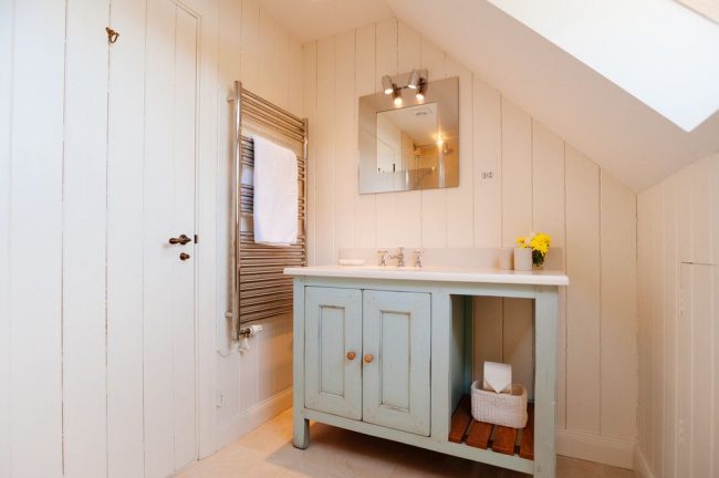 الحمام في المنزل الريفي مع خزائن مدمجة. الخشب هو المادة الرئيسية في التصميم