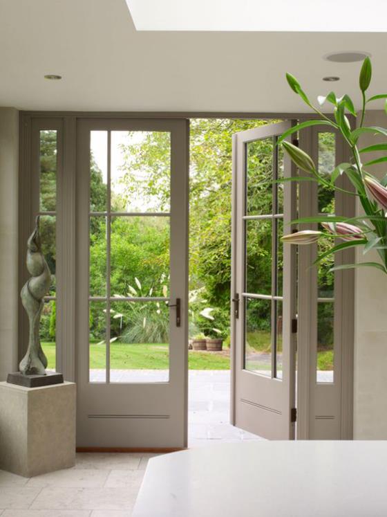 Drzwi balkonowe jedno skrzydło otwarte przejście do zadbanego i mistrzowsko zaprojektowanego posągu ogrodowego z roślinami wewnątrz